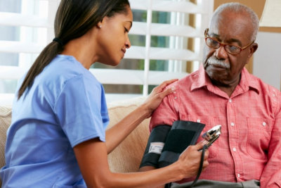 female nurse doing blood pressure monitoring to a senior man